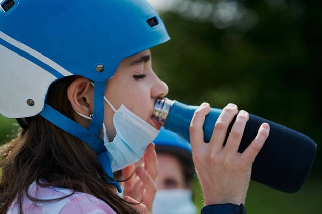 IMAGO Creative: 2022 Farbe des Jahres: Very Peri, Veilchenblau girl with the mask and the riding helmet drinks water from a bottle Pamplona, Navarre, Spain CR_SEBO200707B-408351-01 ,model released, Symbolfoto