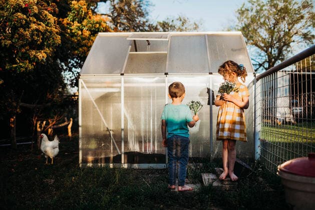 Young kids standing outside backyard green house holding flowers Fort Worth, TX, United States CR_TAHI200701-413970-01 ,model released, Symbolfoto