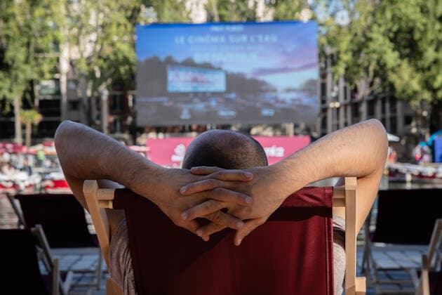 Bilder des Jahres 2020, Entertainment 07 Juli Entertainment Bilder des Tages (200719) -- PARIS, July 19, 2020 (Xinhua) -- A man waits for the screening of the French movie Le Grand Bain in cinema on the water on the Bassin de la Villette, in Paris, Frence, July 18, 2020. The event cinema on the water was organized by Paris Plages (Paris Beaches). Thirty-eight small electric boats and a few deckchairs are installed along the Bassin de la Villette in front of the giant screen. (Photo by Aurelien Morissard Xinhua) FRANCE-PARIS-FLOATING CINEMA 