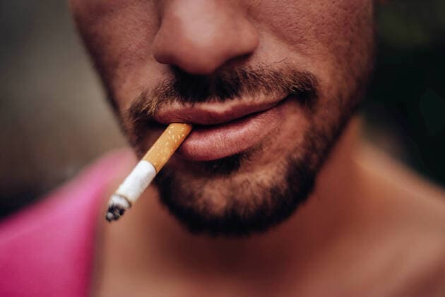 Creative Highlights Symbolfotos Mouth of a young man smiling while smoking a cigarette Madrid, Community of Madrid, Spain CR_DIRR200720A-447643-01 ,model released, Symbolfoto
