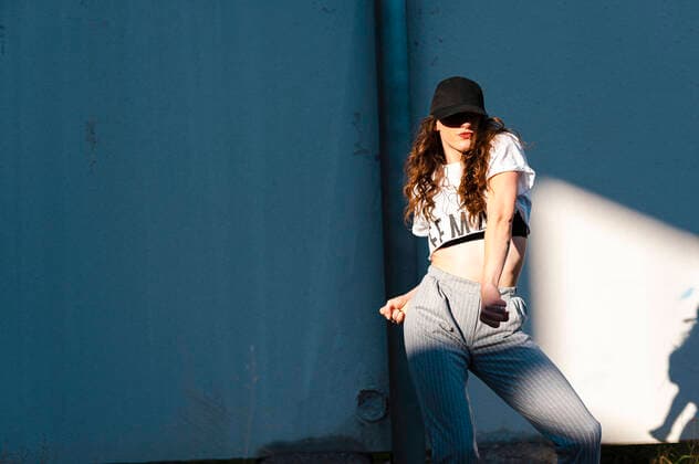 Female hip-hop dancer puckering lips while dancing against white wall during sunny day model released Symbolfoto JMPF00173