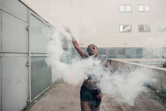 Yyoung woman playing with smoke bomb against building in city model released Symbolfoto MEUF01425