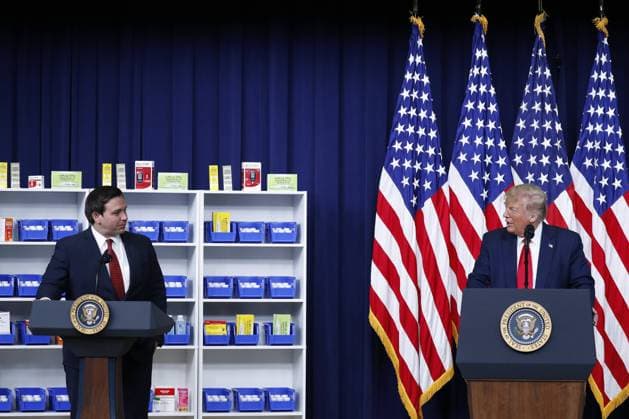 U.S. President Donald Trump, right, speaks to Governor Ron DeSantis, a Republican of Florida, during an executive order signing ceremony in the Eisenhower Executive Office Building in Washington, D.C., U.S., on Friday, July 24, 2020. The orders are subject to regulatory review as the power to lower drug prices through executive order is limited.  WAX20200724169 StefanixReynolds