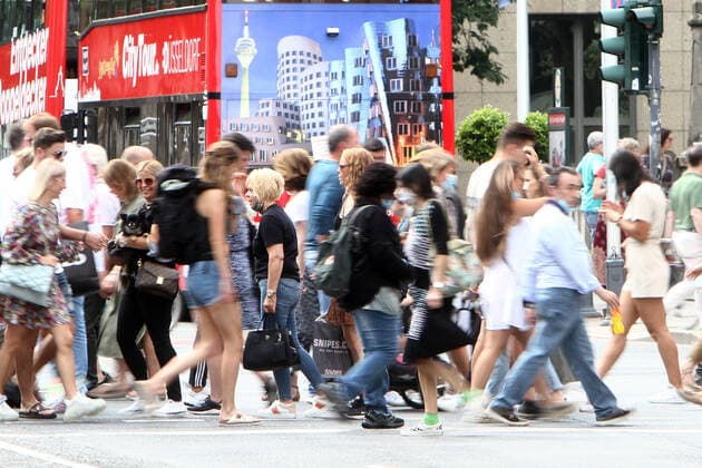 Fußgänger überqueren eine Querstraße der Einkaufsstraße Königsallee in der Innenstadt von Düsseldorf, die nach den Lockerungen der Schutzmaßnahmen und Wiedereröffnung der Geschäfte wieder so wie vor der Coronakrise erscheint: mit großem Andrang von Personen, die weitgehend nicht den gebotenen Mindestabstand zueinander einhalten, Nordrhein Westfalen, Deutschland