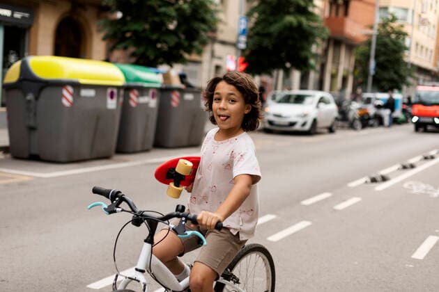 Creative Highlights Symbolfotos Carefree boy holding skateboard while riding bicycle on street model released Symbolfoto VABF03074