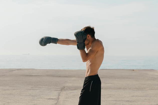 IMAGO Creative: Kulturelle Folgen der Pandemie: Gesundheitsbewußtsein und Alleinsein Shirtless young man practicing boxing while standing at harbor on sunny day model released Symbolfoto VABF03108