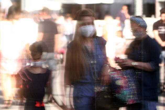 Nach der Lockerung der Schutzmaßnahmen sieht die Einkaufsstraße und Fußgängerzone Neuhauser Straße Kaufingerstraße in der Innenstadt von München wieder so wie vor der Coronakrise aus: mit großem Andrang von Personen, die oft nicht den gebotenen Mindestabstand zueinander einhalten. Passanten mit Mundschutz spiegeln sich in einem Schaufenster, Bayern, Deutschland