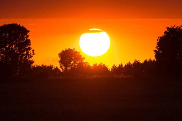 IMAGO Creative: Sonnensystem Die Sonne - Symbolbilder News Bilder des Tages Brandenburg, Sonnenuntergang hinter Bäumen Deutschland, Brandenburg - 28.07.2020: Im Bild ist der Sonnenuntergang von einem Feld in Brandenburg aus zu sehen. Brandenburg Deutschland *** Brandenburg, sunset behind trees Germany, Brandenburg 28 07 2020 The picture shows the sunset from a field in Brandenburg Brandenburg Germany
