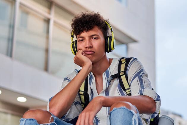 Boring young afro with headphones on sitting on the street Elche, Valencian Community, Spain CR_CRBL200728-457603-01 ,model released, Symbolfoto