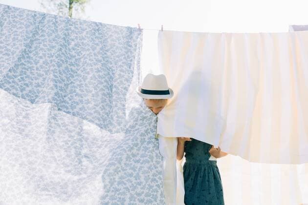 siblings hiding behind the washing drying on the line at home Norrtälje, Stockholm County, Sweden CR_RABE200715-422355-01 ,model released, Symbolfoto