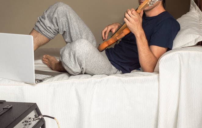 IMAGO Creative, Jahreszeit Herbst, Ferien Young man lying on a bed playing electric bass. Madrid, Community of Madrid, Spain CR_SCOVMN200724-459102-01 ,model released, Symbolfoto