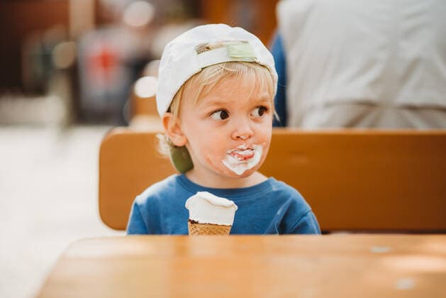 IMAGO Creative: Ruhe im Chaos Young blonde boy with dirty face eating ice cream with a cap on Munich, BY, Germany CR_TANI200722-375389-01 ,model released, Symbolfoto