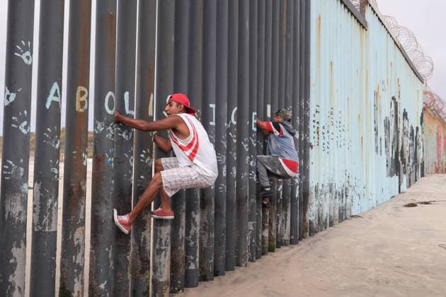 Migrants climb the wall that divides Mexico from US Migrant walking at the beach of Tijuana in an area that is restricted by the COVID-19 contingency. Tijuana Chihuahua Mexico Copyright: DavidxPeinado