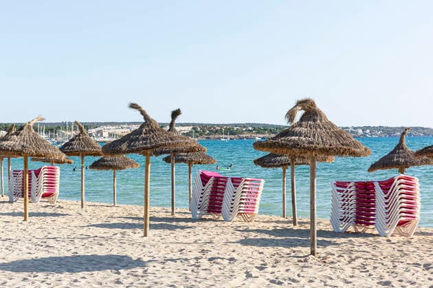 SPANIEN, MALLORCA, PALMA DE MALLORCA, 07.08.2020 - Gestapelte Sonnenliegen und Sonnenschirme an einem leeren Strandabschnitt der Playa de Palma in der Abendsonne am frühen Abend. Im Vergleich zu den Vorjahren sind weniger Touristen vor Ort. Grund ist die aktuell herrschende Corona-Pandemie.