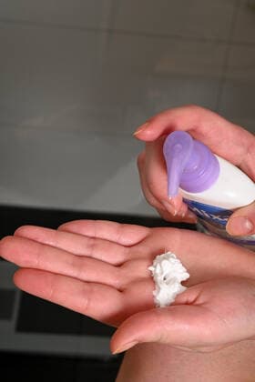 Symbolbild- junge Frau (model released) cremt sich ihre Beine mit Bodylotion ein