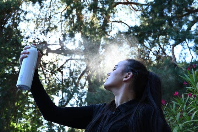 Symbolbild- junge Frau (model released) erfrischt sich mit Wasser-Spray bei hohen Temperaturen