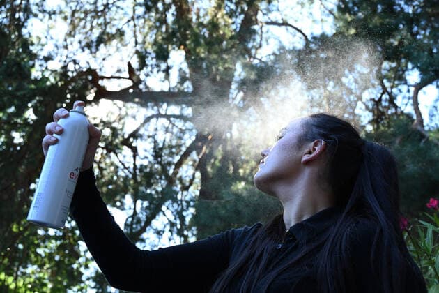 Symbolbild- junge Frau (model released) erfrischt sich mit Wasser-Spray bei hohen Temperaturen