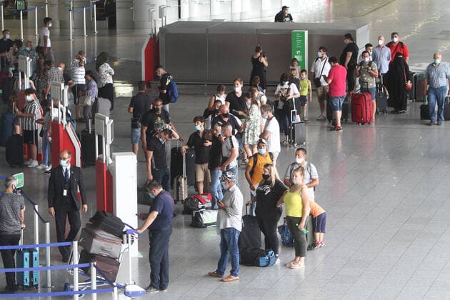 Nach dem Wegfall der meisten Reisewarnungen während der Coronakrise nimmt der Flugverkehr langsam wieder Fahrt auf. Wartende Fluggäste mit Reisegepäck stehen mit Mund-Nase-Abdeckung Schlange an den Abfertigungsschalter n im Terminal 1 in der Abflughalle B im Flughafen Frankfurt, Hessen, Deutschland