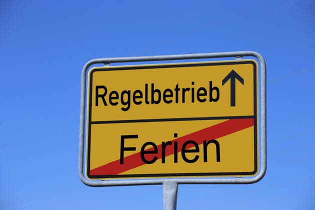 Symbolbild: Ortsausgangsschild mit dem Schriftzug Ferien Regelbetrieb - Fotomontage