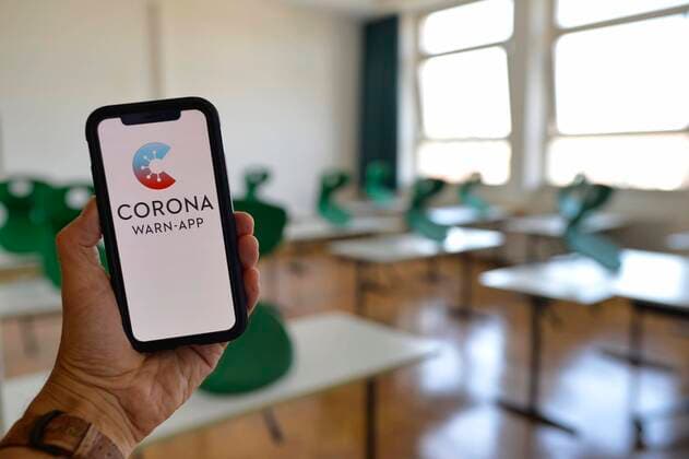 Hand hält Smartphone mit Corona Warn-App im Klassenzimmer, Corona-Krise, Deutschland, Europa Copyright: imageBROKER/MichaelxWeber iblimw05825448.jpg
