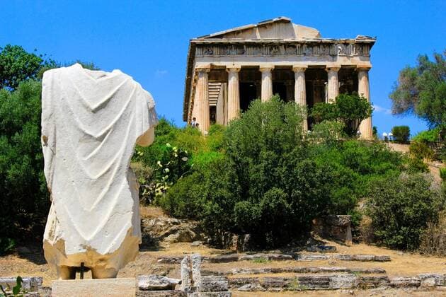 Greece, Athens, July 27 2020 - The Temple of Hephaestus or Hephaisteion at the Ancient Agora archaeological site with the backside of the statue of the Roman Emperor Hadrian in foreground. Copyright: xx