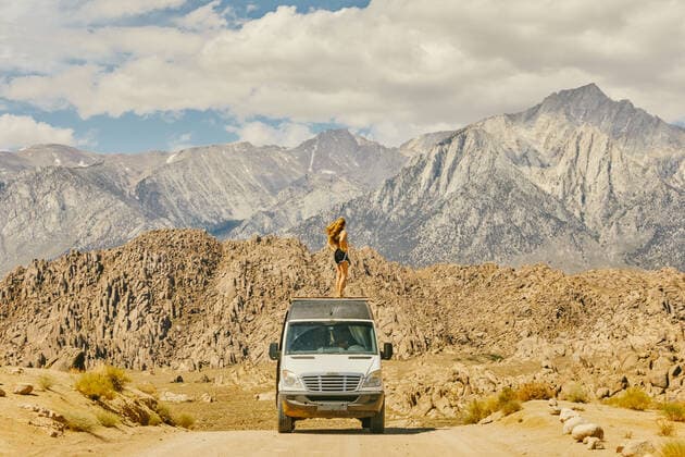 IMAGO Creative: Klimawandel - Nachhaltiges Reisen Young woman on roof of camper van on road in northern California. Lone Pine, CA, United States CR_JUSLKY200806-466838-01 ,model released, Symbolfoto ,property released
