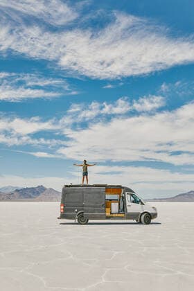 Young man standing on roof of camper van in Bonneville Salt Flats. Salt Lake City, UT, United States CR_JUSLKY200806-466993-01 ,model released, Symbolfoto ,property released