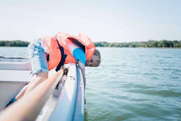 young boy dipping his hand in the water whilst on a boat in summer Norrtälje, Stockholm County, Sweden CR_RABE200812-471636-01 ,model released, Symbolfoto