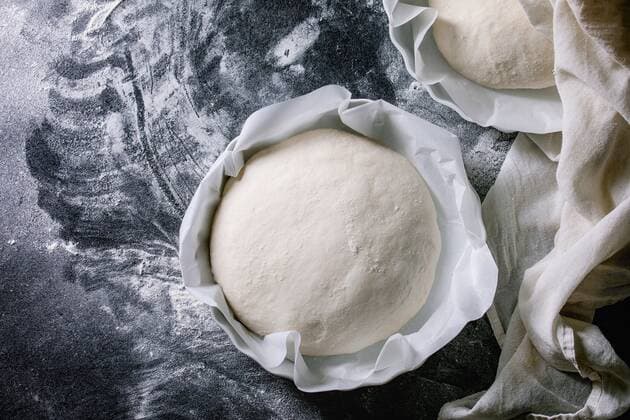 Process of making homemade bread. Fresh dough redy for baking on baked paper over black table with flour. Home bread baking. Photo series. Flat lay, space ÂNatashaBreen REDA&CO 1028_29_NBR8111