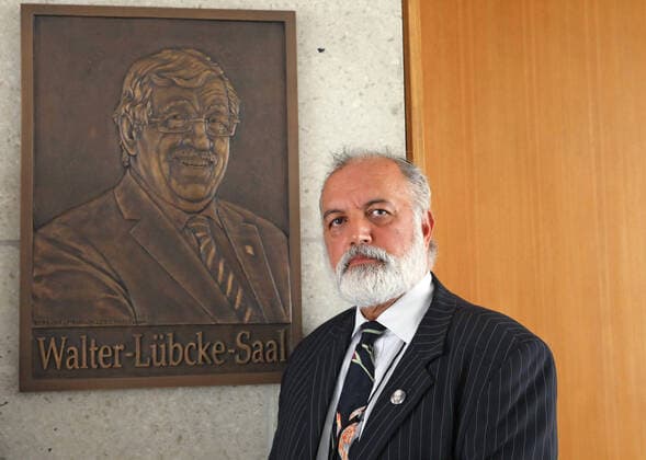 Kuenstler Berahna Massoum vor der Bronzetafel (Foto vom 21.08.2020). Zum Gedenken an dem am 2. Juni 2019 mutmasslich von einem Rechtsextremisten ermordeten Kasseler Regierungspraesidenten Walter Luebcke (Lübcke) wurde am Freitag (21.08.2020) vor dem grossen Sitzungssaal eine Bronzetafel mit dem Konterfei des Verstorbenen enthuellt, die der aus Afghanistan stammende Kuenstler Berahna Massoum geschaffen hat. Zugleich wurde der Saal in Walter-Luebcke-Saal umbenannt (Foto v.li.: v.l. Hermann-Josef Klueber (Regierungspraesident Kassel), Irmgard Braun-Luebcke (Witwe von Walter Luebcke), Berahna Massoum (Kuenstler). (Siehe epd-Meldung vom 21.08.2020) Bronzetafel erinnert an Walter Luebcke