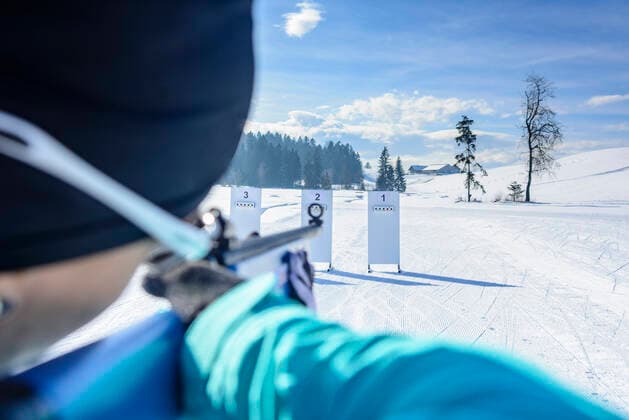 Wintersportler beim Biathlon Freizeit-Biathleten beim Schießen mit einem Lasergewehr an einem kalten und sonnigen Wintertag Biathletin beim anvisieren einer Zielscheibe Sulzberg Nordic Zentrum Vorarlberg Österreich *** Winter sportsmen at the biathlon Leisure biathletes shooting with a laser rifle on a cold and sunny winter day Biathlete aiming at a target Sulzberg Nordic Center Vorarlberg Austria