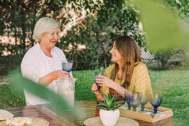 Smiling mother and daughter enjoying drinks while talking in yard model released Symbolfoto property released ERRF04159
