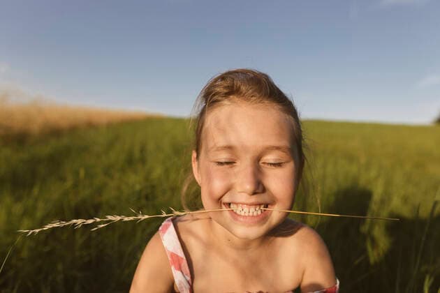 IMAGO Creative: 2021 Favoriten Close-up of smiling girl with eyes closed sitting on land against clear sky during sunset model released Symbolfoto KMKF01435