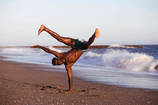 Shirtless African man doing handstand at beach against clear sky model released Symbolfoto property released LJF01711