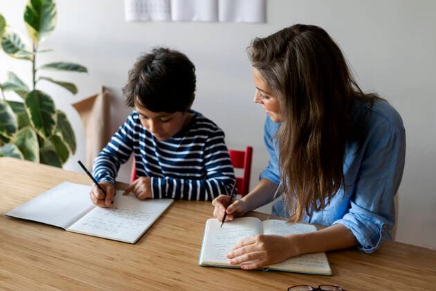IMAGO Creative: NGO, Ausbildung für Kinder Young woman sitting with student doing homework on table at home model released Symbolfoto property released VABF03252