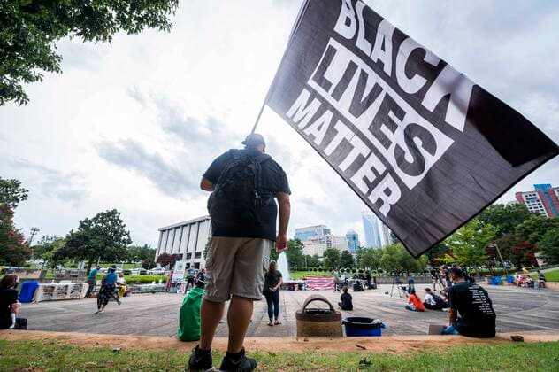 News Bilder des Tages August 24, 2020, Charlotte, North Carolina, USA: A Black Lives Matter supporter waves a flag during a protest against the RNC. Charlotte Uprising, a community coalition dedicated to ending violence against Black and marginalized people, hosted the protest against the Republican National Convention at Marshall Park in Uptown Charlotte. Charlotte USA - ZUMAme2_ 20200824_zaf_me2_030 Copyright: xSeanxMeyersx
