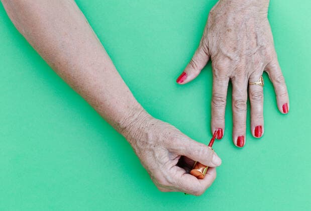 Elderly painting her nails in red with a green background, flat on top Nerva, AL, Spain CR_JURA200824-478387-01 ,model released, Symbolfoto