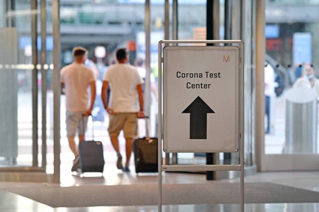 Kostenlose Corona Tests an deutschen Flughaefen,so wie hier am Flughafen Franz Josef Strauss in Muenchen am 24.08.2020. Reisende mit Mundschutz,Maske und Gepaeck nach der Ankunft-passieren ein Hinweisschild fuer den Coronatest.Ankommende Passagiere bekommen am Flughafen ab sofort einen kostenlosen Corona-Test. Es ist ein freiwilliges Angebot - ueber verpflichtende Tests von Rueckkehrern aus Risikogebieten wird weiter diskutiert. Reisende, die aus dem Urlaub zurueckkommen, koennen sich kostenlos auf das Coronavirus testen lassen.
