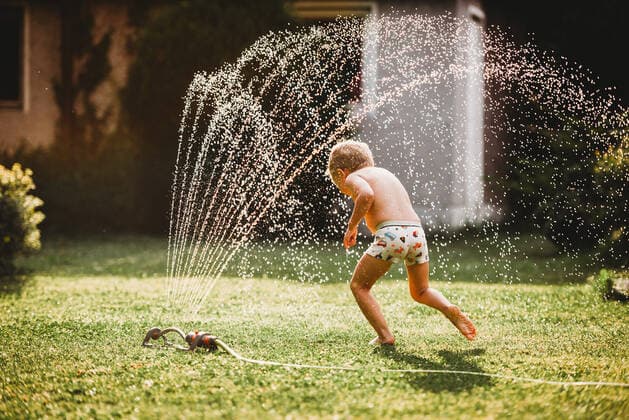 IMAGO Creative: Sommer, Sommertage im Garten Young white boy running under the water from the sprinkler in garden Munich, BY, Germany CR_TANI200906-480761-01 ,model released, Symbolfoto