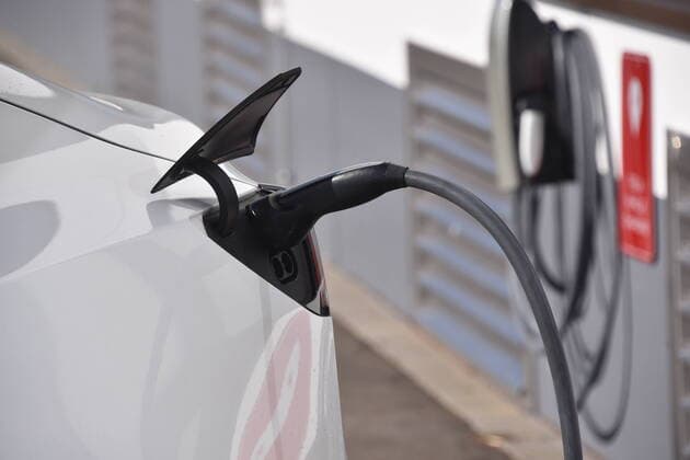 Ein Tasla Model 3 wird an der Ladestation für TESLA Elektrofahrzeuge geladen , Hersteller von Elektrofahrzeugen, am Gebäude der Tochtergesellschaft Tesla Grohmann Automation