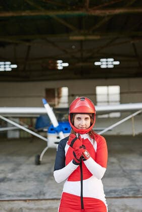 Young female skydiver in a plane hangar with a plane behind her Castellón de la Plana, Valencian Community, Spain CR_BVBE200909-496500-01 ,model released, Symbolfoto