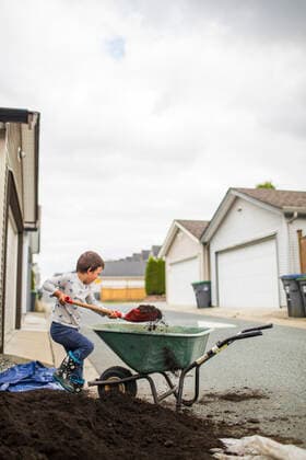 IMAGO Creative, Lifestyle, Frühling in der Stadt Young boy lifting shovel full of soil into wheelbarrow in back alley Surrey, BC, Canada CR_JDIP200913A-495006-01 ,model released, Symbolfoto ,property released