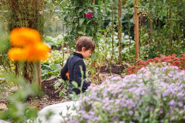 IMAGO Creative, Ostern, Bräuche, Osterspaziergang A small child walks alone through a flower-filled garden path Columbus, OH, United States CR_RETI200909B-478617-01 ,model released, Symbolfoto