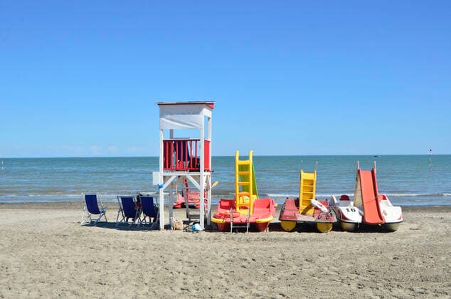 Bunte Boote am Strand von Albarella, Italien-Urlaub 2020, Strandabschnitt an der Adria, Markierungen auf dem Boden für Abstandsregeln, Hygieneregeln, Italien ist eines der Länder in Europa, das am härtesten von der Corona-Pandemie getroffen wurde, Strand: pro Sonnenschirm muss zehn Quadratmeter Platz eingehalten werden, der Mindestabstand zwischen zwei Sonnenliegen beträgt 1,50 Meter, Reisende, Touristen, Strandbesuch, Italienurlaub, Liegen müssen nach jedem Besucherwechsel desinfiziert werden. Vorabbuchungen für den Zugang zu Strandbädern sollen verhindern, dass die Menschen zu dicht aneinander in der Sonne braten. Infektionen, Covid 19, Corona Abstandsregeln am Strand in Italien