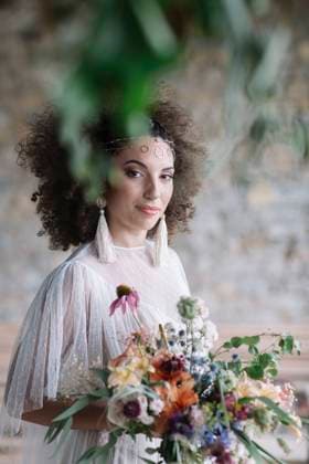 Young woman in wedding dress holding bouquet while standing against wall model released Symbolfoto ALBF01496