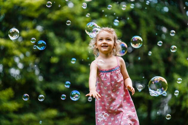 Weltkindertag am 20. September Happy girl enjoying while running amidst bubbles at park model released Symbolfoto DIGF12918