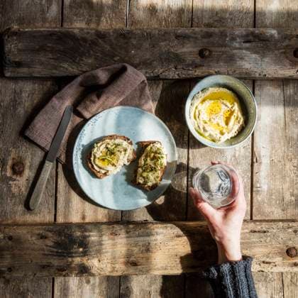 IMAGO Creative, Food, Hummus Hand of woman holding glass of water and plate with bread slices with hummus and sprouts model released Symbolfoto EVGF03726