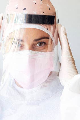 Dentist in protective suit adjusting face mask at office model released Symbolfoto JCMF01280