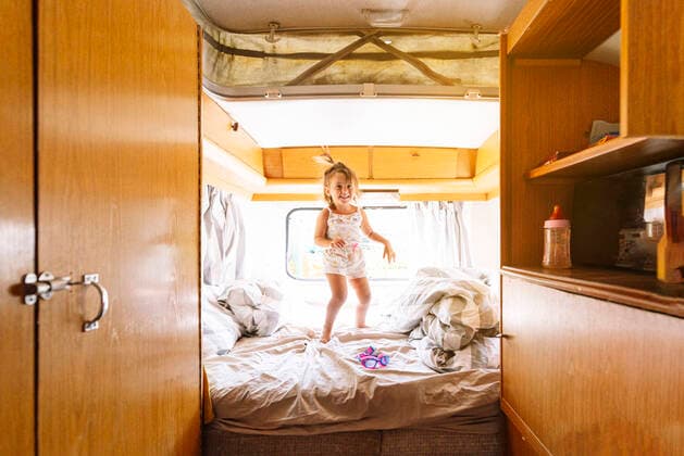 IMAGO Creative: Klimawandel - Nachhaltiges Reisen Cheerful girl jumping on bed in motor home model released Symbolfoto JCMF01334