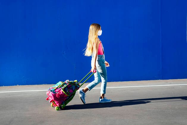 IMAGO Creative: NGO, Ausbildung für Kinder Blond girl walking with schoolbag on street against blue wall model released Symbolfoto JCMF01378